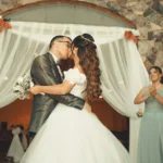 A joyful wedding moment capturing the bride and groom sharing a kiss surrounded by bridesmaids.