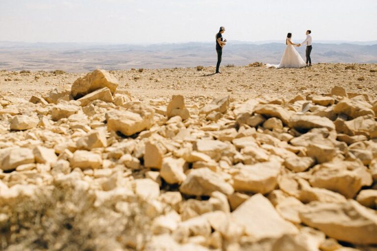 A romantic wedding photoshoot in a rocky desert with a couple and a musician.