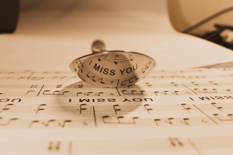 A reflective spoon casting text 'I Miss You' onto sheet music, sepia tone.