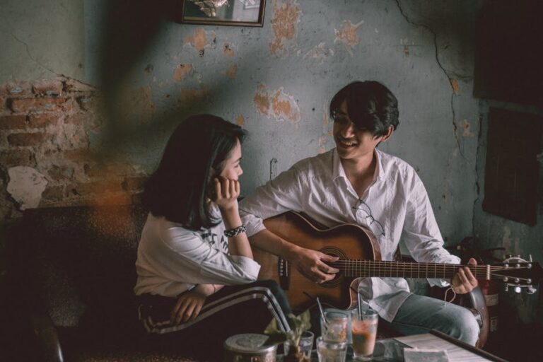 A couple enjoys an intimate music session indoors with a guitar.