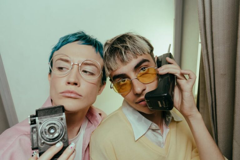 Two stylish teenagers posing with retro accessories in a photobooth, capturing a vintage vibe.
