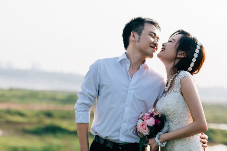 Couple embracing in a sunny outdoor wedding with a lush background in Hanoi, Vietnam.